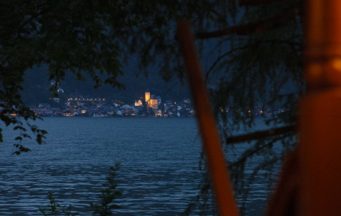Vue sur le lac et une ville illuminée de nuit depuis l’hébergement glamping Park am See à Obertraun, Autriche.