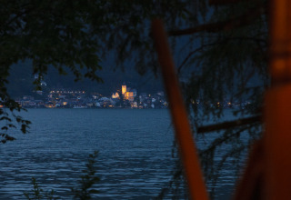 Vista sul lago e sulla città illuminata di notte dal glamping Park am See a Obertraun, Austria.