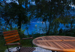 Coin salon extérieur avec table et chaise en bois devant un lac paisible au crépuscule à Obertraun.