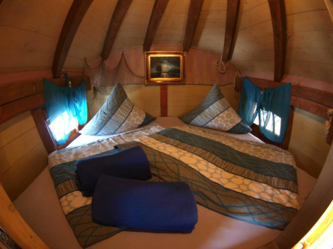 Gemütlicher Innenraum einer Baumhütte bei Het Culturele Eiland Einsiedler - Boomhutten in Sachsen.