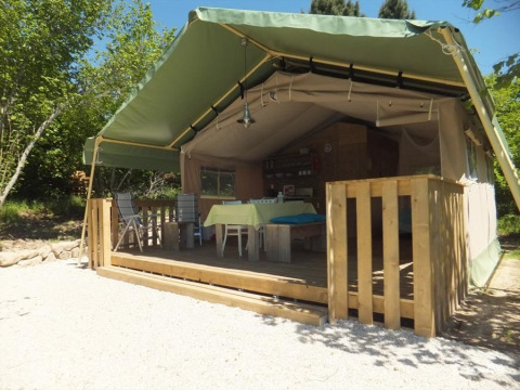 Glamping Chave Grande safaritent met houten terras en comfortabele stoelen, buiten in de zon.