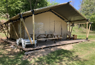 Glamping Chave Grande - Safaritenten: Luxuriöses Safarizelt mit Holzterrasse, Stühlen und Picknicktisch im Grünen.