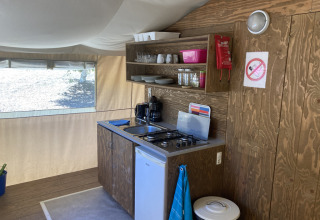 Cucina attrezzata in tenda safari presso Glamping Chave Grande con fornello, frigo e utensili.