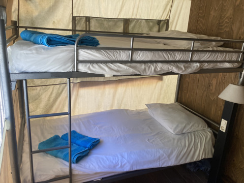 Interieur van Glamping Chave Grande - Safaritenten met stapelbedden en blauwe handdoeken in de safaritent.