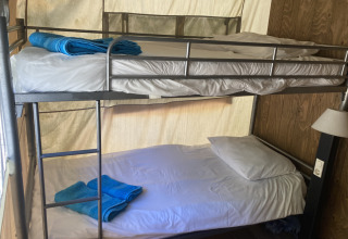 Interieur van Glamping Chave Grande - Safaritenten met stapelbedden en blauwe handdoeken in de safaritent.