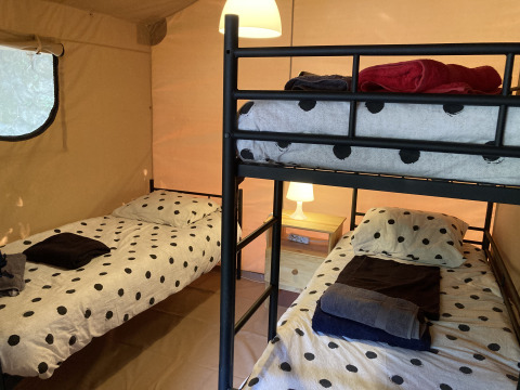 Binnenzicht van een Glamping Chave Grande - Safaritenten met stapelbed en eenpersoonsbedden met stippen.