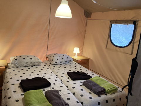 Deux lits simples avec housses à pois dans une tente de luxe Glamping Chave Grande - Safaritenten, ambiance nature.