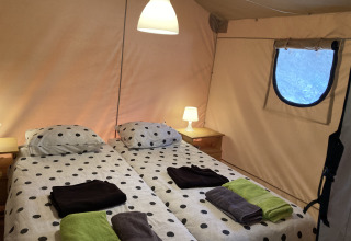 Dos camas individuales con ropa de cama a lunares en Glamping Chave Grande - Safaritenten, comodidad en la naturaleza.