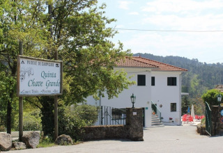 Entrance to Glamping Chave Grande - Safaritenten, showing sign, the main building, and trees in a scenic area.