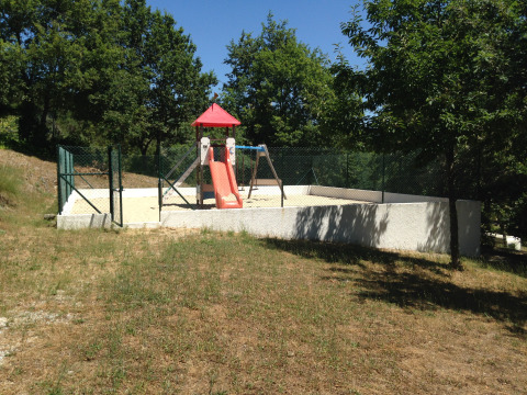 Area giochi recintata con scivolo e altalene circondata da alberi presso Glamping Chave Grande - Safaritenten.