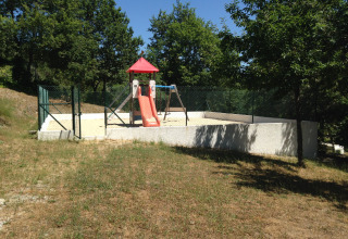 Eingezäunter Spielplatz mit Rutsche und Schaukeln im Grünen bei Glamping Chave Grande - Safaritenten.