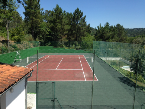 Tennis court surrounded by trees at Glamping Chave Grande - Safaritenten under clear blue skies.