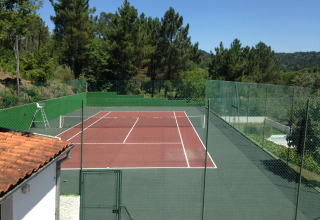 Tennisplatz im Grünen bei Glamping Chave Grande - Safaritenten, umgeben von hohen Bäumen.