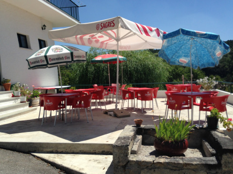 Outdoor terrace at Glamping Chave Grande - Safaritenten featuring red chairs, umbrellas, and a green view.