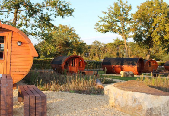Glamping accommodation in barrel-shaped wooden lodges at Campingpark Heidewald, surrounded by nature.