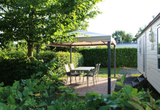 Udendørs glampingområde på Campingpark Heidewald med pavillon, havemøbler og grøn beplantning.