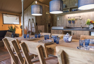 Lyst og rustikt køkken- og spisestueområde i glamping-lodge, Campingpark Heidewald, Tyskland.