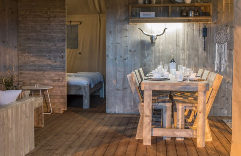 Interior of a glamping lodge at Campingpark Heidewald, Germany, with rustic wooden furniture and dining table.