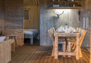 Indretning af glamping-lodge i Campingpark Heidewald Tyskland med rustikke træmøbler og spisebord.