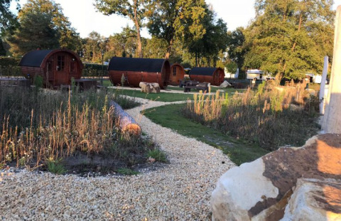 Glamping accommodation with wine barrel cabins and lodges at Campingpark Heidewald, Germany, in sunlight.