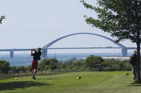Golfista sul campo con vista sul ponte Fehmarn presso il campeggio Wulfener Hals sul Mar Baltico.