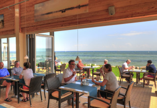 Des personnes dînent dans un restaurant avec vue sur la mer au camping Wulfener Hals, mer Baltique.