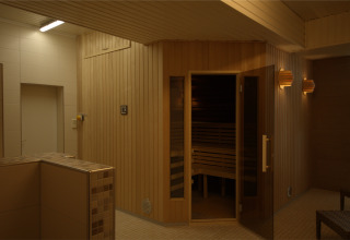 Sauna moderne au Camping en vakantiepark Wulfener Hals avec murs en bois et éclairage doux près de la mer Baltique.