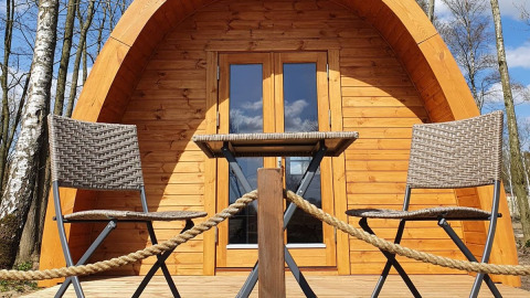 Glamping accommodatie 'Nord-Ostsee Camp - Pods Sleeswijk-Holstein' met twee stoelen en een tafel voor een houten pod.