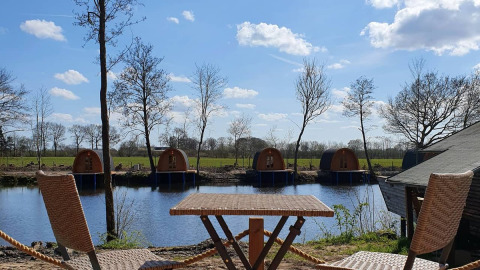 Blick auf See und Bäume mit Nord-Ostsee Camp - Pods Schleswig-Holstein Unterkünften von einer Terrasse.