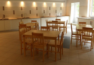 Cuisine commune au Nord-Ostsee Camp - Pods Schleswig-Holstein avec tables et chaises en bois.