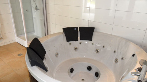 Jacuzzi moderno con reposacabezas negros y ducha al fondo en Nord-Ostsee Camp - Pods Schleswig-Holstein.