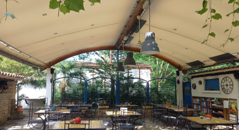 Zona pranzo all'aperto coperta con tavoli presso Camping Les Drouilhedes - Tent Lodges Occitanië.