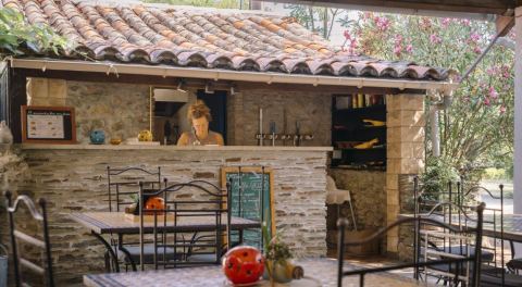 Gemütlicher Außenbereich eines Cafés im Camping Les Drouilhedes - Tent Lodges Occitanië mit Naturstein