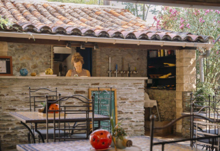 Gemütlicher Außenbereich eines Cafés im Camping Les Drouilhedes - Tent Lodges Occitanië mit Naturstein