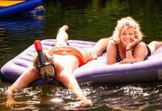 Dos personas se relajan sobre un colchón inflable flotante en el lago en Camping Les Drouilhedes - Tent Lodges Occitanië.