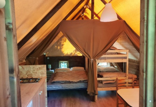 Glamping-Unterkunft mit Betten, Küchenzeile und Esstisch im Zelt auf Camping Les Drouilhedes in Okzitanien.