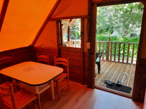 Innenaufnahme einer Glamping-Lodge bei Camping Les Drouilhedes mit Tisch, Stühlen und Terrasse draußen.