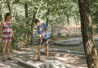 To personer spiller minigolf blandt træerne ved Camping Les Drouilhedes Tent Lodges Occitanië
