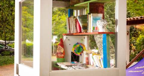 Outdoor-Bücherschrank mit Büchern, Gnomenfigur und Deko bei Camping Les Drouilhedes in Okzitanien.