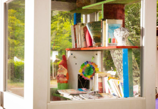Outdoor-Bücherschrank mit Büchern, Gnomenfigur und Deko bei Camping Les Drouilhedes in Okzitanien.