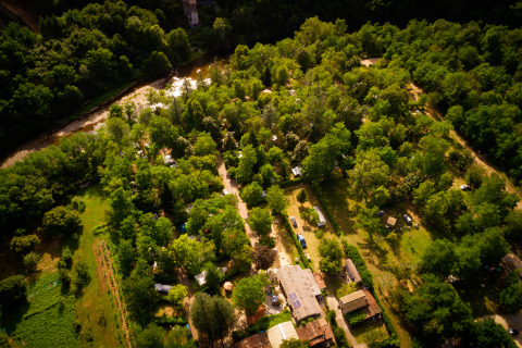 Vista aerea di Camping Les Drouilhedes con Tent Lodges in Occitania, immerso nel verde vicino a un fiume.