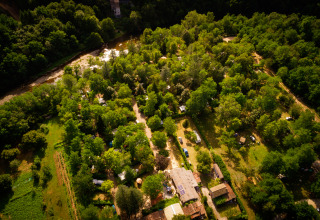 Vista aerea di Camping Les Drouilhedes con Tent Lodges in Occitania, immerso nel verde vicino a un fiume.