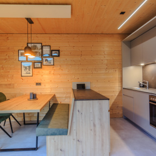 Modern kitchen and dining area with wooden walls at Wirthshof Resort Comfort chalet near Lake Constance, glamping.