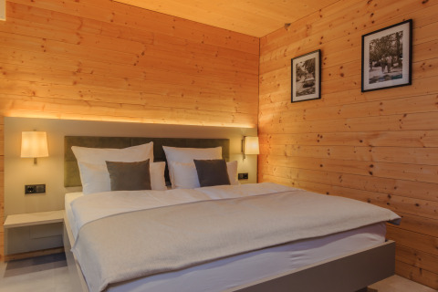 Gezellige slaapkamer in het Wirthshof Resort Comfort chalet aan de Bodensee met hout en moderne inrichting.
