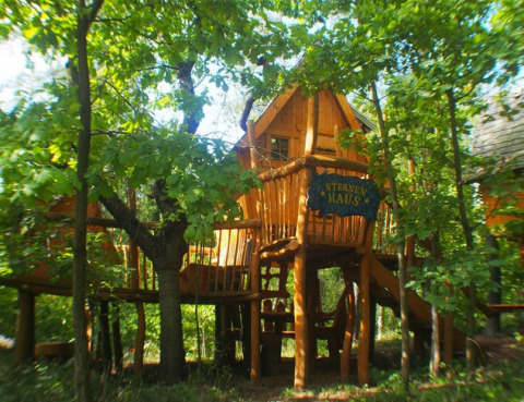 Baumhaus-Glamping-Unterkunft im Familiepark Sottrum, Niedersachsen, umgeben von grünen Bäumen.