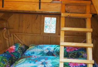 Innenansicht einer gemütlichen Baumhütte im Familiepark Sottrum mit buntem Bettzeug und Hochbett.