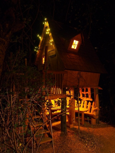 Beleuchtetes Baumhaus bei Familiepark Sottrum Boomhutten Nedersaksen, nächtliche Glamping-Unterkunft im Wald.
