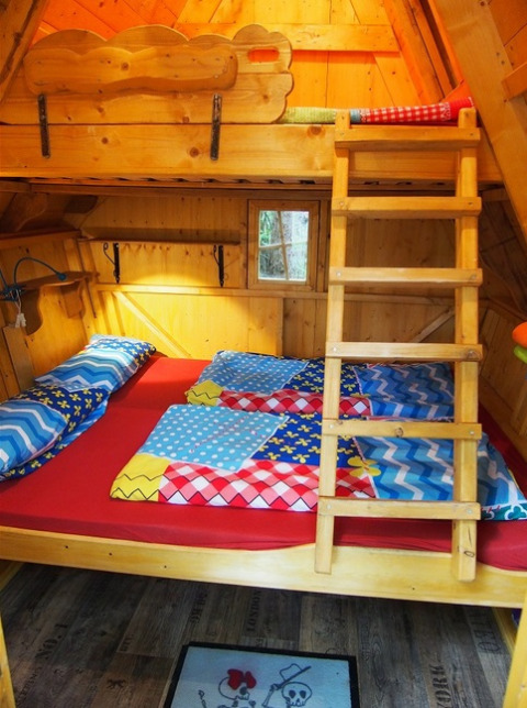 Boomhut glamping in Familiepark Sottrum met stapelbedden, kleurrijk beddengoed en houten inrichting.
