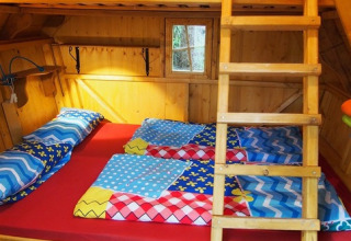 Glamping treehouse at Familiepark Sottrum with bunk beds, colorful bedding, and wooden cabin interior.