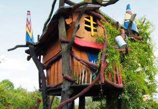 Colorful treehouse accommodation at Familiepark Sottrum, set among greenery and whimsical branches.
